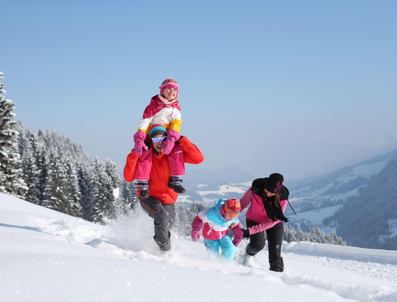 Family playing in the snow in the Kleinwalsertal valley